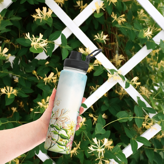 Handheld honeysuckle birth flower water bottle in front of garden trellis